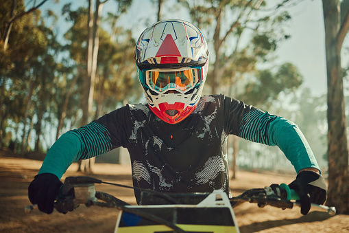 Bmx, moto cross and motorbike sports on a dirt bike in a mountain forest for race and cycling. Fitness, extreme sport and training of an athlete ready to start competition on a outdoor road track