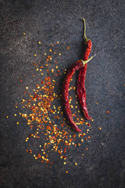 istock Dry chili pepper flakes. Crushed red peppers on black table. Top view. 1473450608