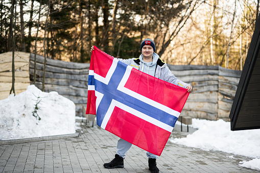 Portrait of man holding Norway flag. Scandinavian culture, norwegian people.