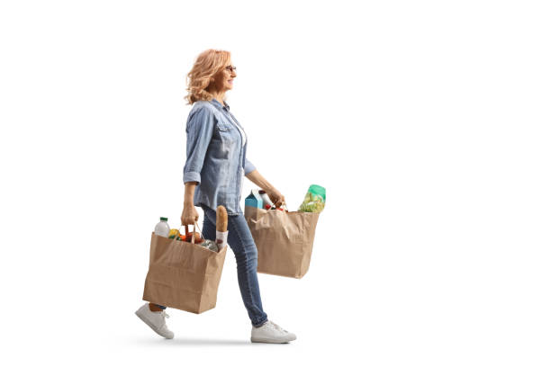 Full length profile shot of a mature woman carrying grocery bags and walking stock photo
