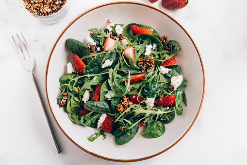 Healthy Salad made from Green Salad Leaves, Rocket Salad, Slices of Fresh Strawberries, pieces of Feta Cheese and Different Seeds.