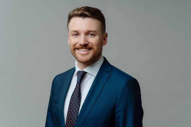 istock Cheerful male CEO in suit smiling at camera while posing against grey background 1473451278