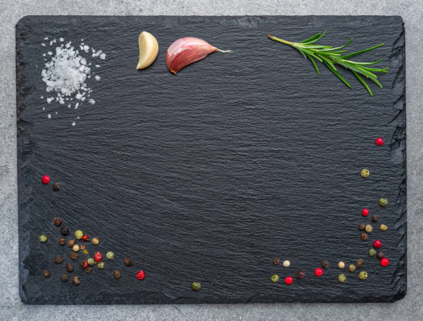 istock Natural stone black slate serving plate with seasonings and spices arranged as a frame. Flat lay. 1473452816