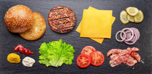 istock Cheeseburger ingredients on natural stone black slate serving plate. Flat lay. 1473452925