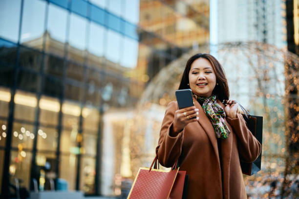 istock Happy Asian woman using app on mobile phone while spending her day in shopping. 1473455091