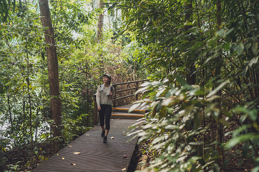 Asian Chinese woman walking through a path in the forest