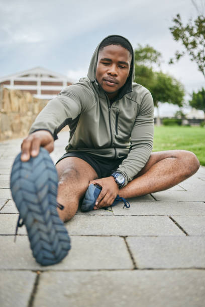 istock Fitness, park or black man stretching in exercise for body training or workout with focus in Detroit, USA. Legs, mindset or healthy sports athlete with running goals, motivation or mission in city 1473459540