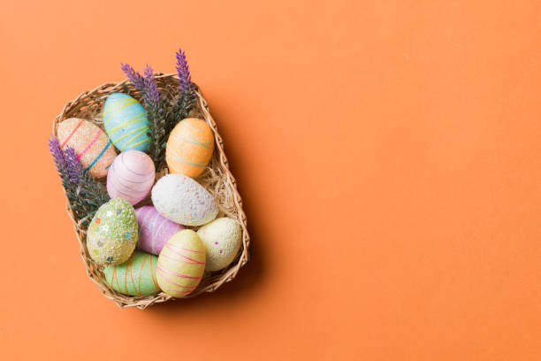 istock Colorful Easter eggs in wicker basket against colored background, closeup. top view with copy space 1473460842