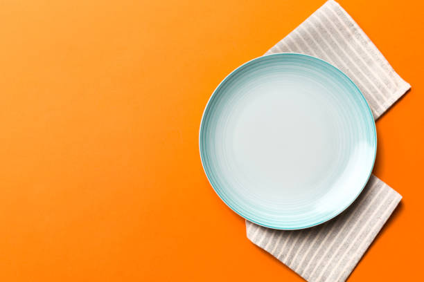 istock Top view on colored background empty round blue plate on tablecloth for food. Empty dish on napkin with space for your design 1473460902
