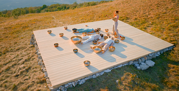 High angle view of female therapist playing ring gong while performing music therapy during sunset.