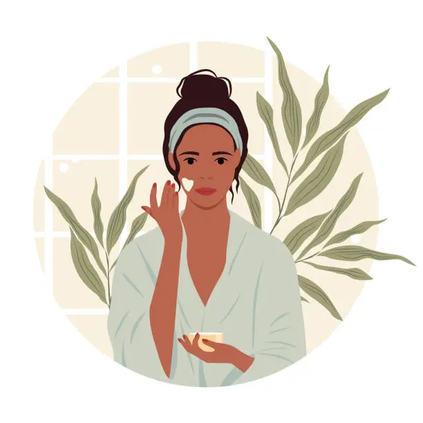 Vector illustration of Vector illustration of a dark-skinned girl in a bathrobe applying cream on her face in the bathroom.