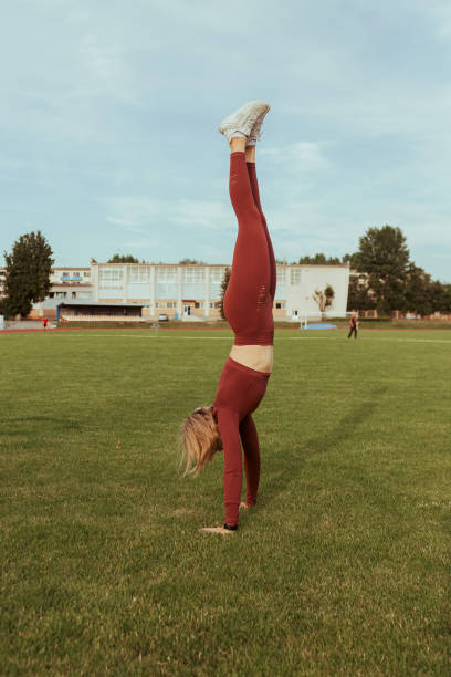 athlète féminine montrant un handstand lors d’un entraînement sportif dans un stade - inversion yoga photos et images de collection