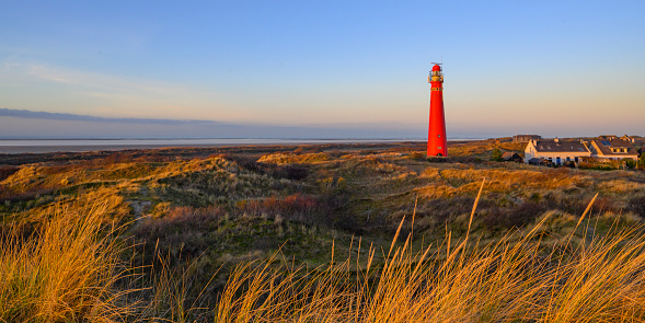 Schiermonnikoog panoramic view in the dunes with the lighthouse during sunset at the wadden island during a beautiful winter day. Schiermonnikoog is part of the Frisian Wadden Islands and is known for its beautiful natural scenery, including sandy beaches, rolling dunes, and lush wetlands.