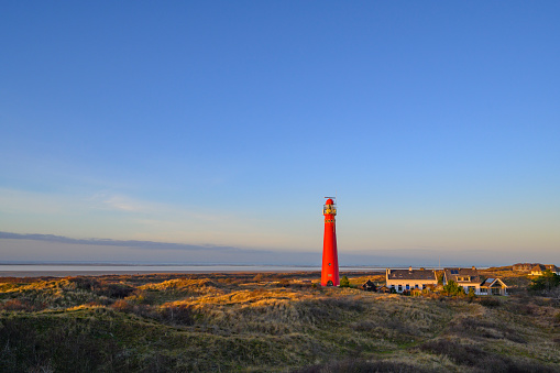 Schiermonnikoog panoramic view in the dunes with the lighthouse during sunset at the wadden island during a beautiful winter day. Schiermonnikoog is part of the Frisian Wadden Islands and is known for its beautiful natural scenery, including sandy beaches, rolling dunes, and lush wetlands.