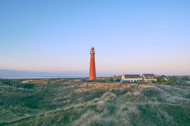 Schiermonnikoog panoramic view in the dunes with the lighthouse during sunset at the wadden island during a beautiful winter day. Schiermonnikoog is part of the Frisian Wadden Islands and is known for its beautiful natural scenery, including sandy beaches, rolling dunes, and lush wetlands.
