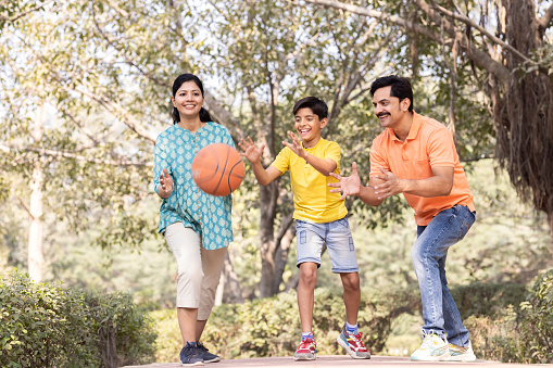 Happy indian family playing with basketball at park