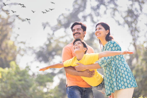 Cheerful parents assisting son in flying at park.