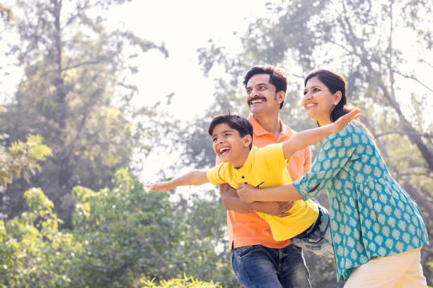 istock Cheerful parents assisting son in flying at park. 1473467341