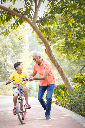 Grandfather teaching grandson to ride bicycle