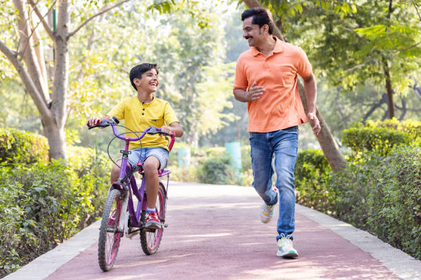 istock Boy learning bicycle with assistance of father at park 1473467584