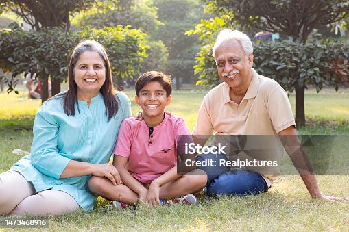 istock Happy grandparents having fun with grandson at park. 1473468916