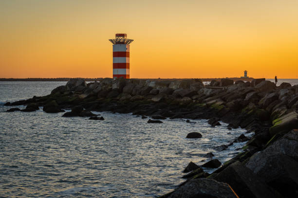 lighthouse at the north pier ijmuiden by sunset with a view on south pier in the distance - ijmuiden imagens e fotografias de stock