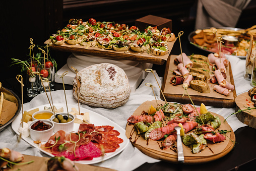 Buffet table. Mini cold snacks, canapes, and appetizers for public catering. Food on wooden plates, serving board on festive table. Buffet. Celebration of birthday party, baptism, wedding, corporate.