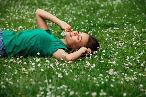 Closeup portrait of attractive woman in spring garden. Beautiful girl in spring landscape background. Springtime. Cover face healthy skin. Beauty clinic skincare organic natural spring