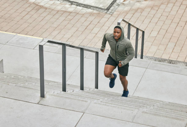 Runner, fitness and city stairs with a sports black man in the city for a cardio or endurance workout. Training, exercise or motivation with a male athlete running or moving up an urban staricase corredor, fitness y escaleras de la ciudad con un hombre negro deportivo en la ciudad para un entrenamiento cardiovascular o de resistencia. entrenamiento, ejercicio o motivación con un atleta masculino corriendo o ascendiendo en un staricase urbano