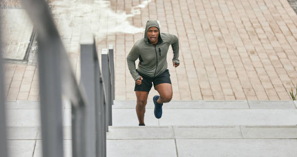 istock Fitness, runner or black man running on stairs for training, exercise or cardio workout in Chicago. Mission, mindset or healthy athlete in hoodie with motivation or sports goals exercising on steps 1473477400