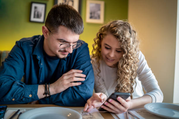 istock Couple looking at a smartphone at the restaurant 1473477639
