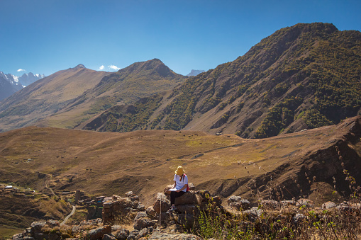A tourist girl sits on a stone in the mountains and looks at the route map for further travel