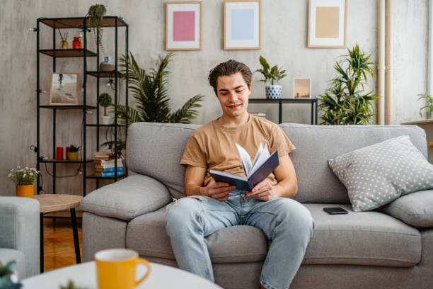 istock Young Man Reading A Book At Home 1473484656