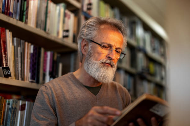 istock Gray-Haired Retired Man Reading A Book At The City Library 1473485192