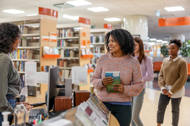 istock Female Students On Line To Check Out Their Books At The Library 1473485247