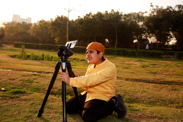 istock Elementary child setting up mobile phone on tripod for photography and video. Young photographer! 1473487094