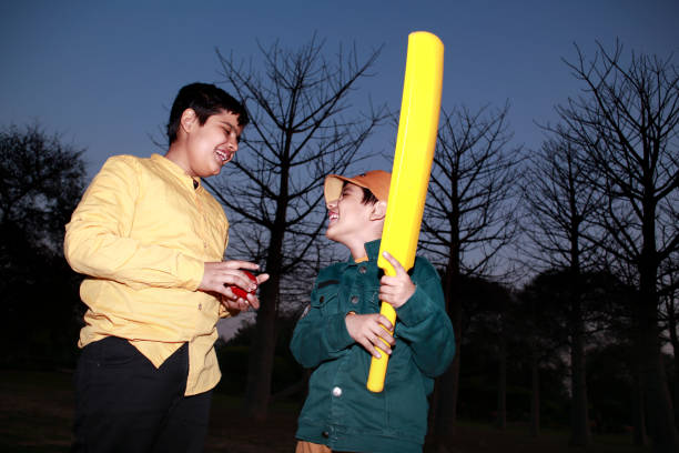Happy indian siblings with bat and ball going to play cricket - concept of friendship, team work, outdoor activities.