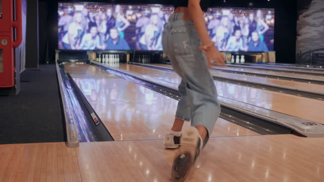 Happy woman winning a strike at bowling ball