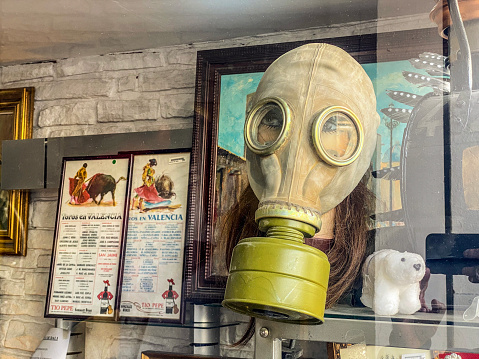 Valencia, Spain - March 8, 2023: Close-up view of female mannequin head wearing a vintage gas mask in antiques store window. The city is plenty of this type of business as there are lots of people interested in this kind of collectibles