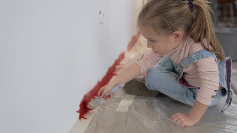 Little girl painting a wall red