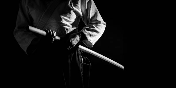 Fighting Pose with Bokken Black and White Banner A person in black hakama standing in fighting pose with wooden sword bokken in black and white. Shallow depth of field. SDF. kendo stock pictures, royalty-free photos & images