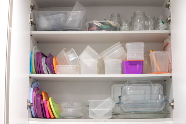 istock Open kitchen cupboard full of plastic and glass containers inside. 1473495563