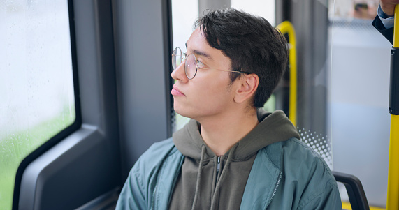 Young male passenger sitting while travelling in public bus.
