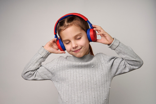 Girl listening music with headphones over white background. Cute girl wearing headphones, enjoying music