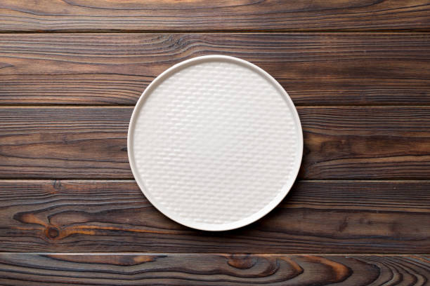 istock Top view of empty light plate on wooden background. Empty space for your design 1473497785