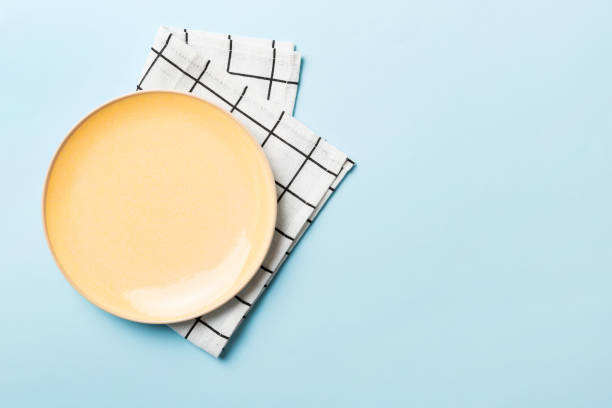 istock Top view on colored background empty round yellow plate on tablecloth for food. Empty dish on napkin with space for your design 1473497800