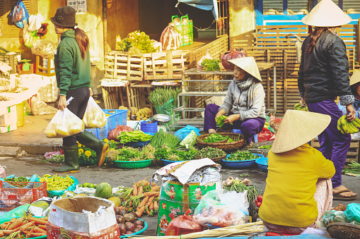 Hoi An, Vietnam - February 7, 2018 : Soft focus on Vietnamese woman selling vegetables on a roadside market in Hoi An, Quang Nam Province, Vietnam.