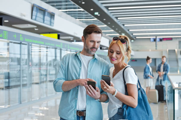 istock Man sharing smart phone with girlfriend at airport 1473500740