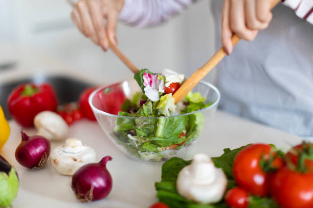 istock Unrecognizable woman making fresh vegetable salad, preparing meal at home 1473500802