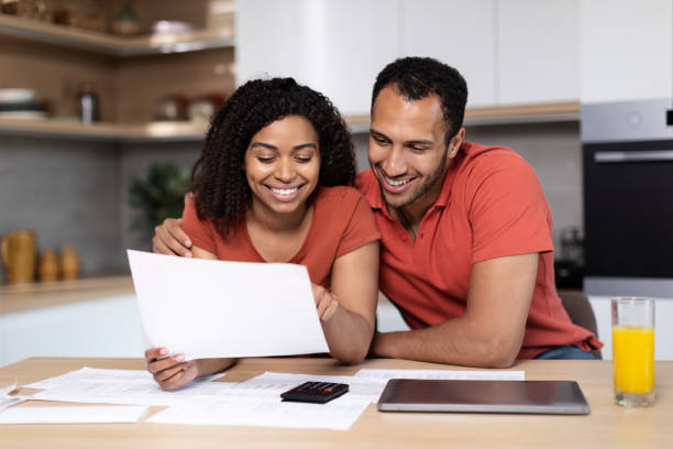 istock Smiling millennial african american wife and husband in same t-shirts work with documents, calculate profit 1473500806